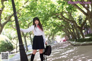 A woman in a school uniform is putting on her hair.