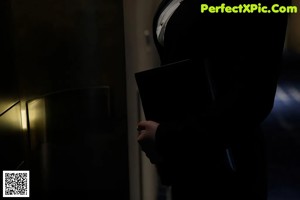 a woman in a black suit standing next to a wall