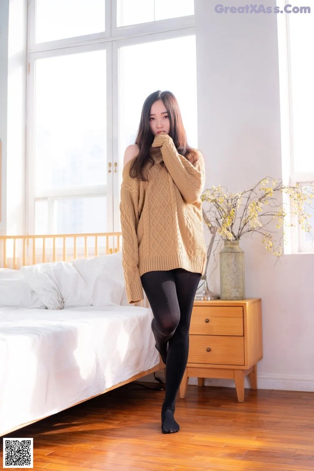 A woman standing in front of a bed in a bedroom.