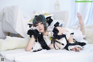 A woman in a maid outfit posing on a bed.