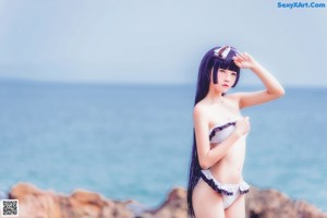 A woman in a bikini posing on the beach.