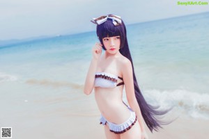 A woman in a white bikini standing on a beach.