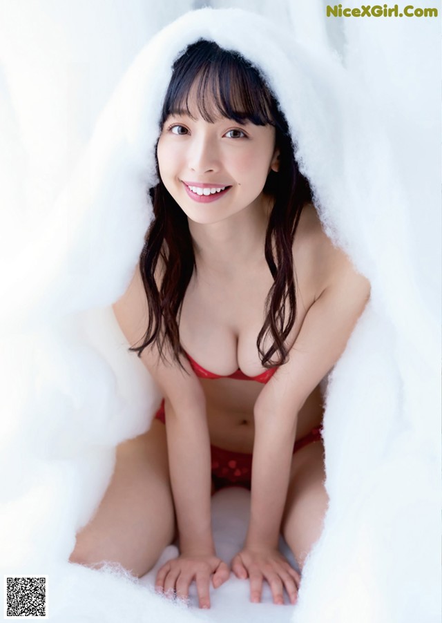 A woman in a red bikini sitting under a white blanket.