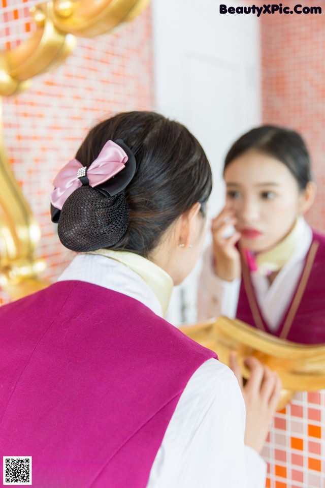 A woman in a pink vest is looking at herself in the mirror.