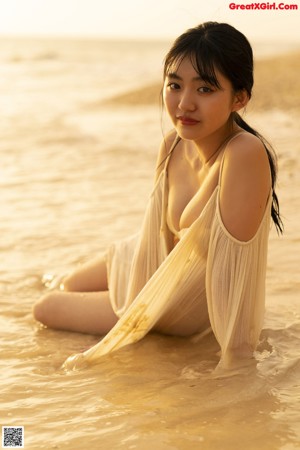 A woman in a bikini standing in the ocean with an inflatable ring.