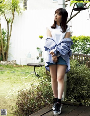 A woman in a blue shirt and yellow skirt eating a piece of food.
