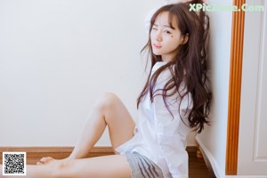 A woman in a white shirt and black shorts posing for a picture.