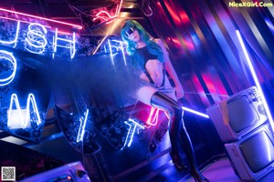 A woman in a black bodysuit and thigh high boots posing in front of a neon sign.