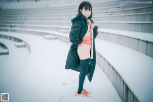 A woman sitting on a wooden bench in the snow.