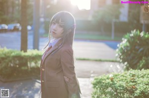 A woman in a school uniform sitting on a stone ledge.