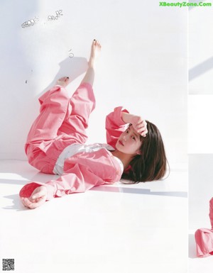 A woman in a pink jumpsuit is posing for a magazine.