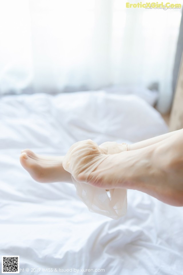 A person putting a pair of white socks on a bed.