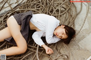 A young woman in a school uniform posing naked on a bed.