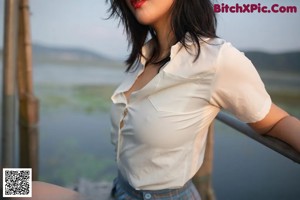 A woman in a white shirt and plaid skirt sitting on a dock.