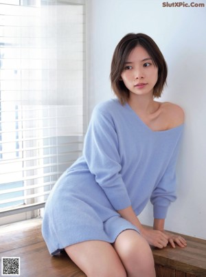 A woman sitting on a window sill holding a glass of wine.