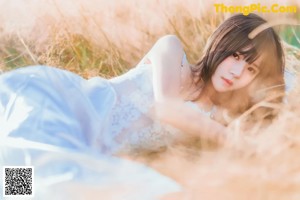 A woman in a white dress sitting in tall grass.