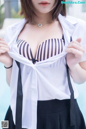 A woman sitting on the ground next to a swimming pool.