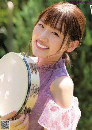 A woman in a yellow top and blue shorts blowing bubbles.