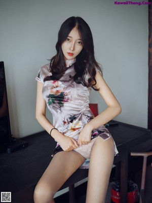 A woman sitting on a chair in front of a television.