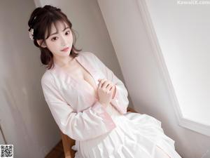 A woman in a yellow kimono sitting on a bed.