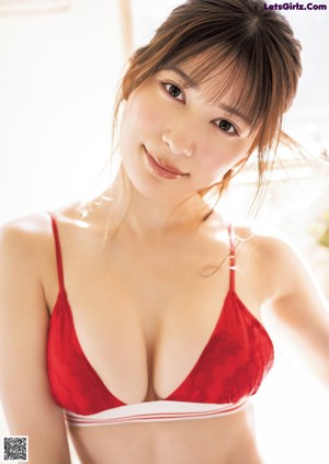 A woman in a red bra top is posing for the camera.