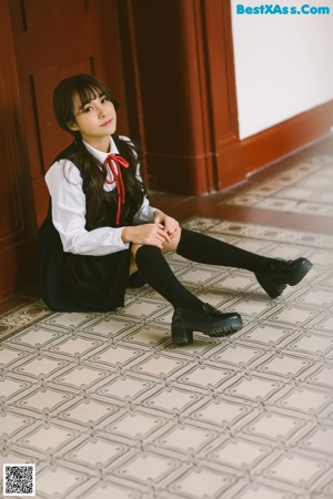A young woman in a school uniform sitting on the grass.