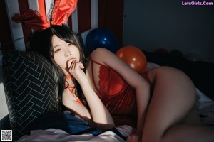 A woman laying on a bed holding a bunch of balloons.