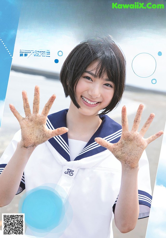 A woman in a sailor outfit with her hands covered in sand.