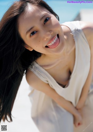 A woman with long brown hair posing on a beach.