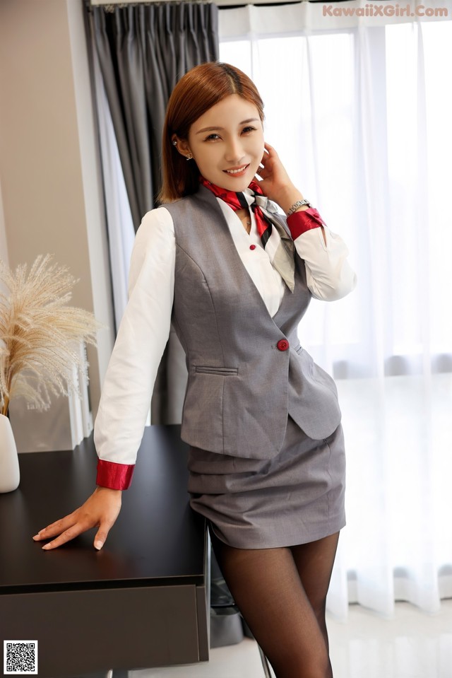 A woman in a gray suit is posing for a picture.