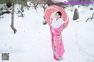 A woman in a pink kimono standing in the snow.