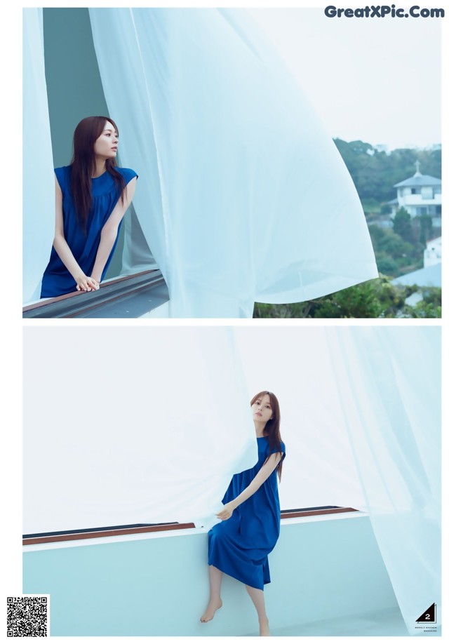 A woman in a blue dress standing on a balcony.